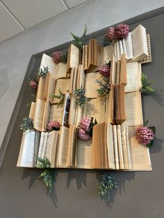 an arrangement of open books with flowers on them and greenery growing out of them