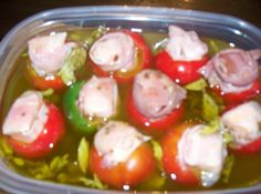 a plastic container filled with lots of different types of tomatoes and meats in oil