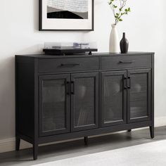 a black sideboard with glass doors and a vase sitting on it's top