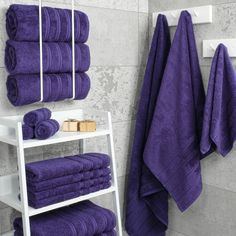 purple towels are stacked on a shelf in the bathroom