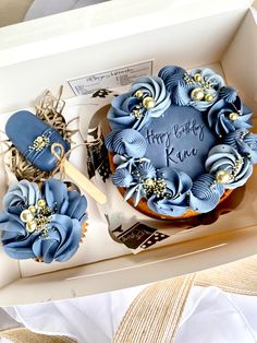 a birthday cake with blue frosting and gold decorations in a box on a table