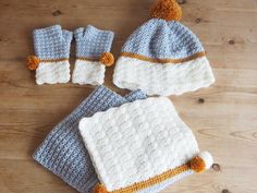 three crocheted hats and two matching mittens on a wooden table with wood flooring