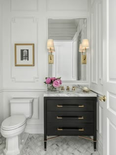 a white and black bathroom with gold accents