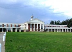 a large white building sitting on top of a lush green field