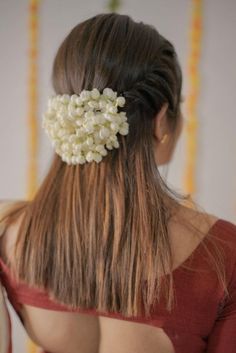 the back of a woman's head with flowers in her hair, wearing a red top