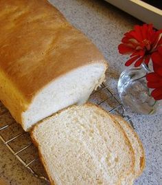 a loaf of white bread sitting on top of a counter next to a glass vase