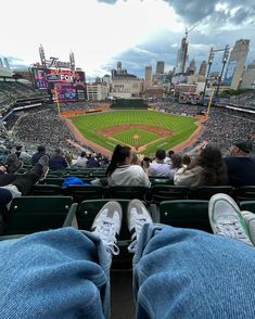 two people sitting in the stands at a baseball game with their feet on the seats