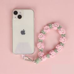 an iphone with a lanyard attached to it next to a phone case on a pink background