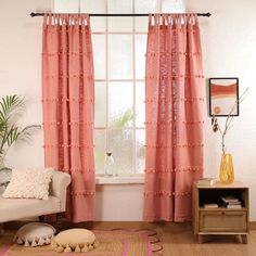 a living room with pink curtains and a white couch in front of a large window