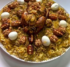 a plate topped with pasta covered in meat and nuts next to an egg on top of it