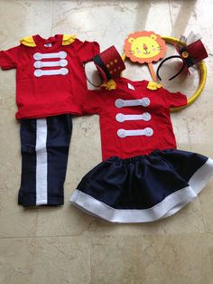 a red shirt and blue skirt are on the floor next to a pair of headbands