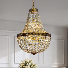 a chandelier hanging from the ceiling over a dining room table with flowers on it