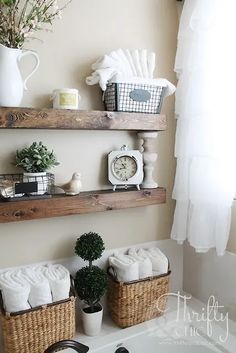 bathroom shelves with towels, plants and other items on them in baskets next to a window