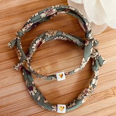 two headbands with flowers on them sitting on a wooden floor next to a white flower