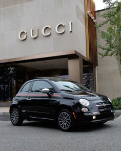 a small black car is parked in front of a gucci store on the street