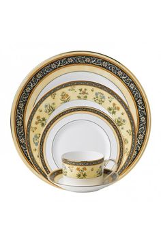 a set of four dinner plates with floral designs and gold trimmings on them