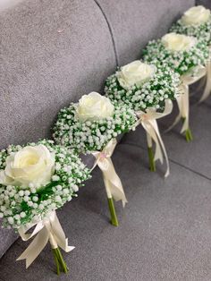 white roses and baby's breath are arranged on the back of a gray bench