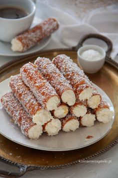 powdered sugar covered bananas on a plate next to a cup of coffee