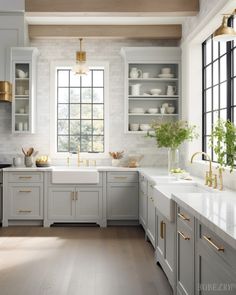 a large kitchen with white cabinets and gold trim on the windows, along with wooden flooring