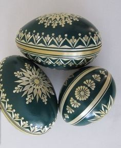 three green and gold decorated eggs sitting next to each other