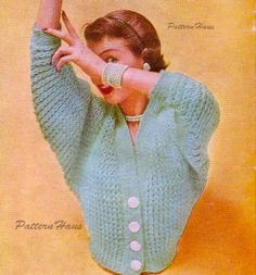 a woman is wearing a green sweater and holding her hand up in the air while posing