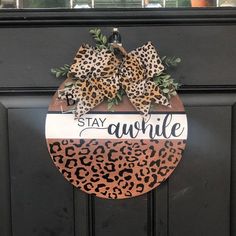 a leopard print door hanger that says stay awhile