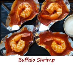 four pieces of food with sauce and shrimp in them on tin foil next to a glass of milk