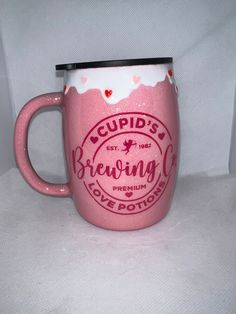 a pink coffee mug with the words cupid's brewing on it