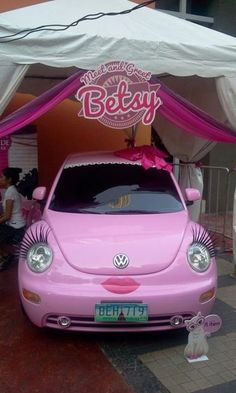 a pink car is parked under a canopy