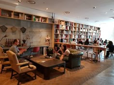 people are sitting around in the library with bookshelves on the wall behind them