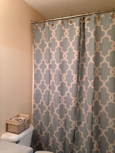 a white toilet sitting next to a blue shower curtain in a bathroom under a window