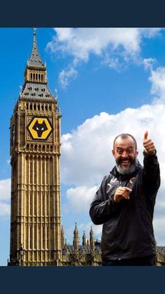 a man standing in front of the big ben clock tower with his hand up and thumbs up