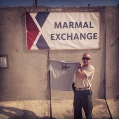 a man standing in front of a marmal exchange sign holding up a white flag