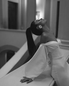 black and white photo of woman in dress sitting on counter with head tilted to the side