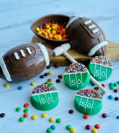 chocolate football candies with sprinkles and candy on the table next to them