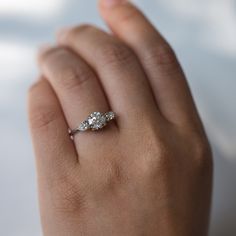 a woman's hand with a three stone diamond ring on her left hand,