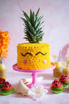 a pineapple cake with eyes drawn on it and cupcakes next to it