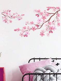 a bed with pink sheets and pillows in front of a wall decal that has flowers on it