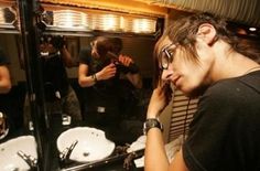 a young man is brushing his teeth in front of the mirror while another person looks on