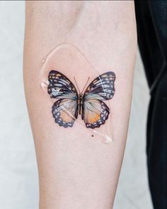 a small butterfly tattoo on the right arm and leg, with an orange stripe around it's wings