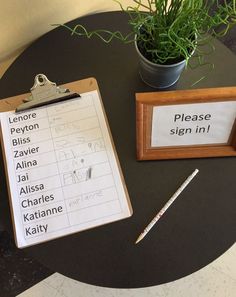 a clipboard with some writing on it next to a potted plant