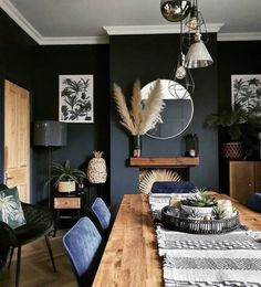 a dining room with blue chairs and a wooden table in front of a black wall