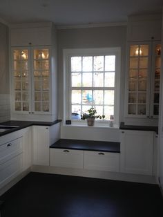 a kitchen with white cabinets and black counter tops in front of a large open window