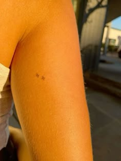 the back of a woman's arm with small stars on it