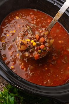 a crock pot filled with beef and bean soup, garnished with a spoon