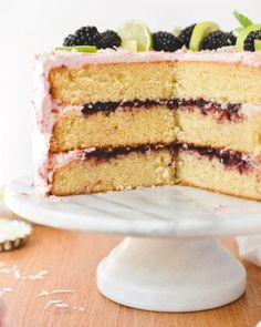 a close up of a slice of cake on a plate with berries and limes