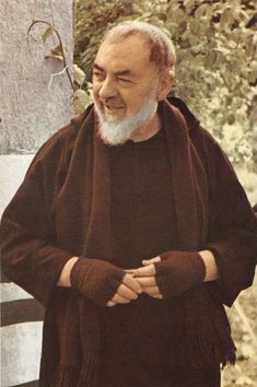 an old man with a white beard is standing in front of a fence and trees