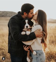 a man and woman kissing while holding a dog