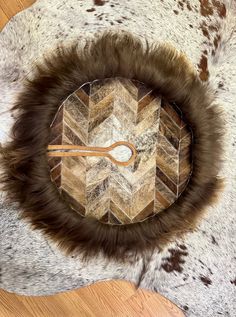 a fur covered clock sitting on top of a wooden table next to a cowhide rug