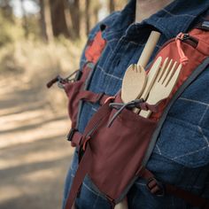 a person wearing a backpack with utensils in their back pocket and holding a knife and fork